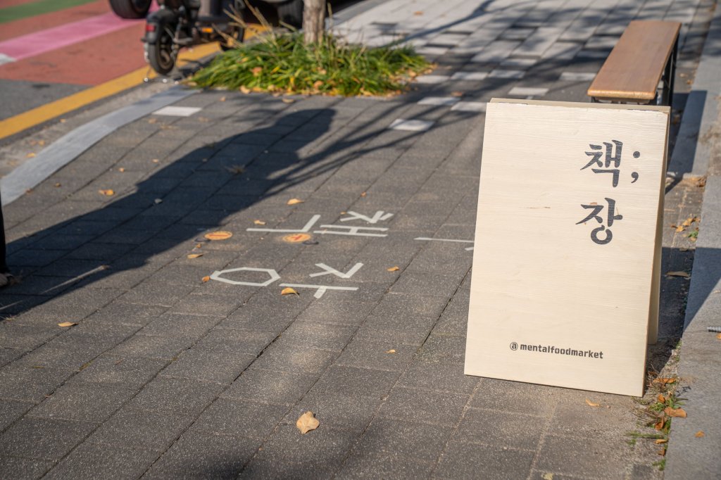 보도 위 책;장 입간판과 바닥에 테이프로 붙인 책;장 글자