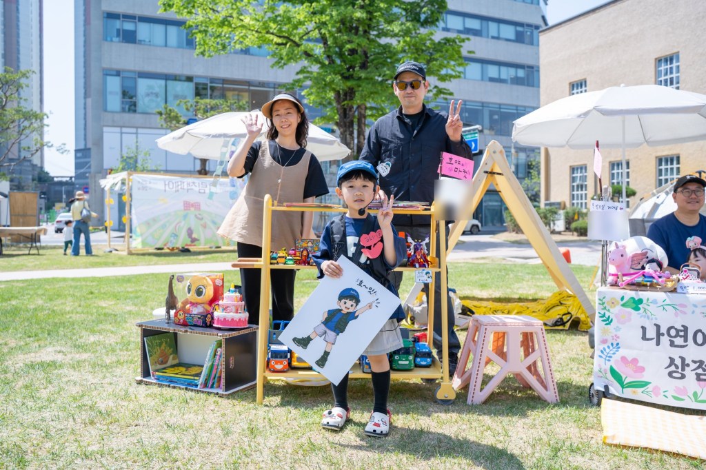 직접 그린 캐릭터 팻말을 든 ‘호야 마켓’ 어린이 셀러와 부모