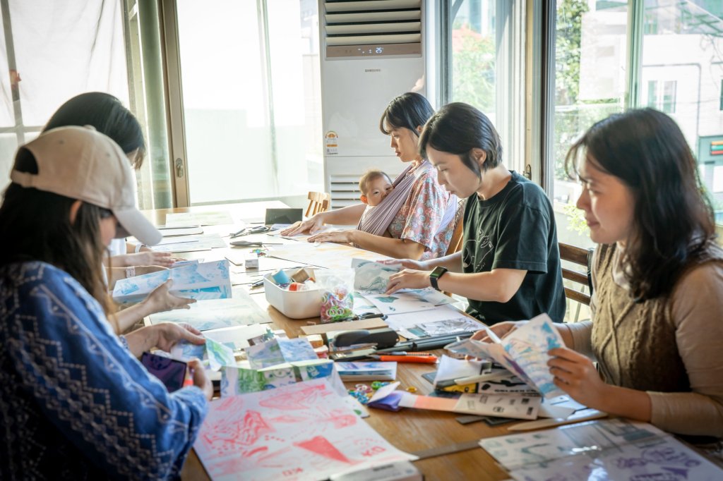 창가 테이블에 둘러앉아 인쇄물을 정리하는 참여자들