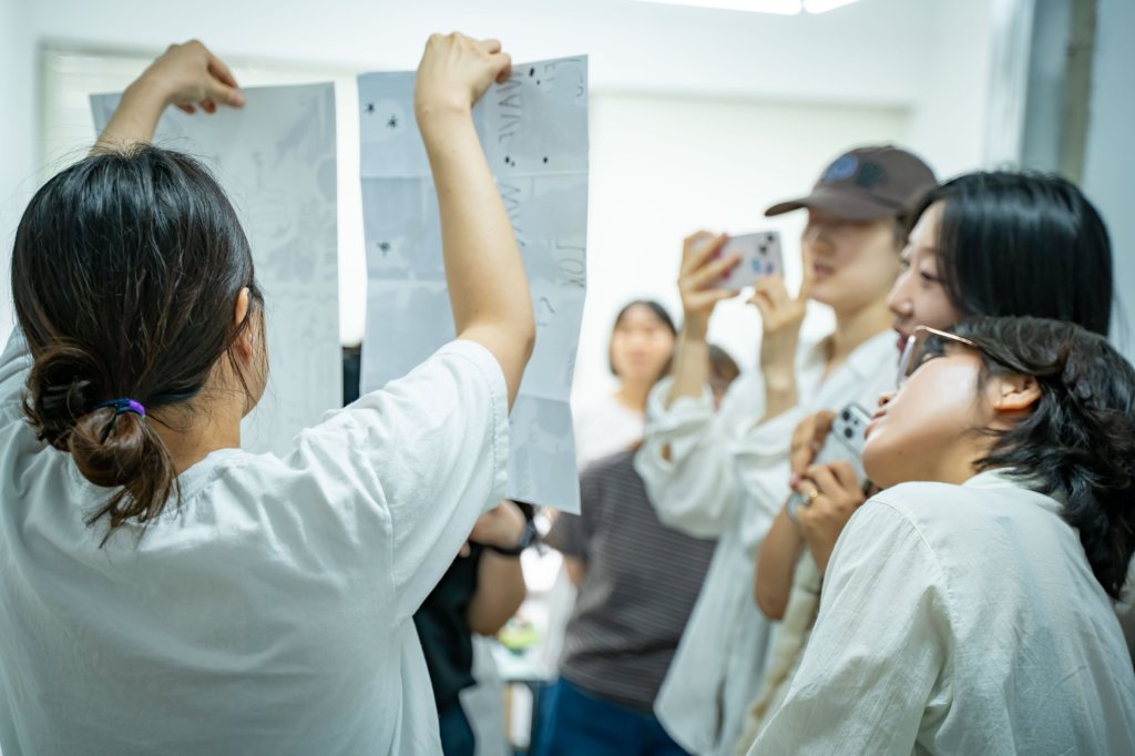 출력한 원고를 들어 보이는 진행자와 사진을 찍는 참여자들