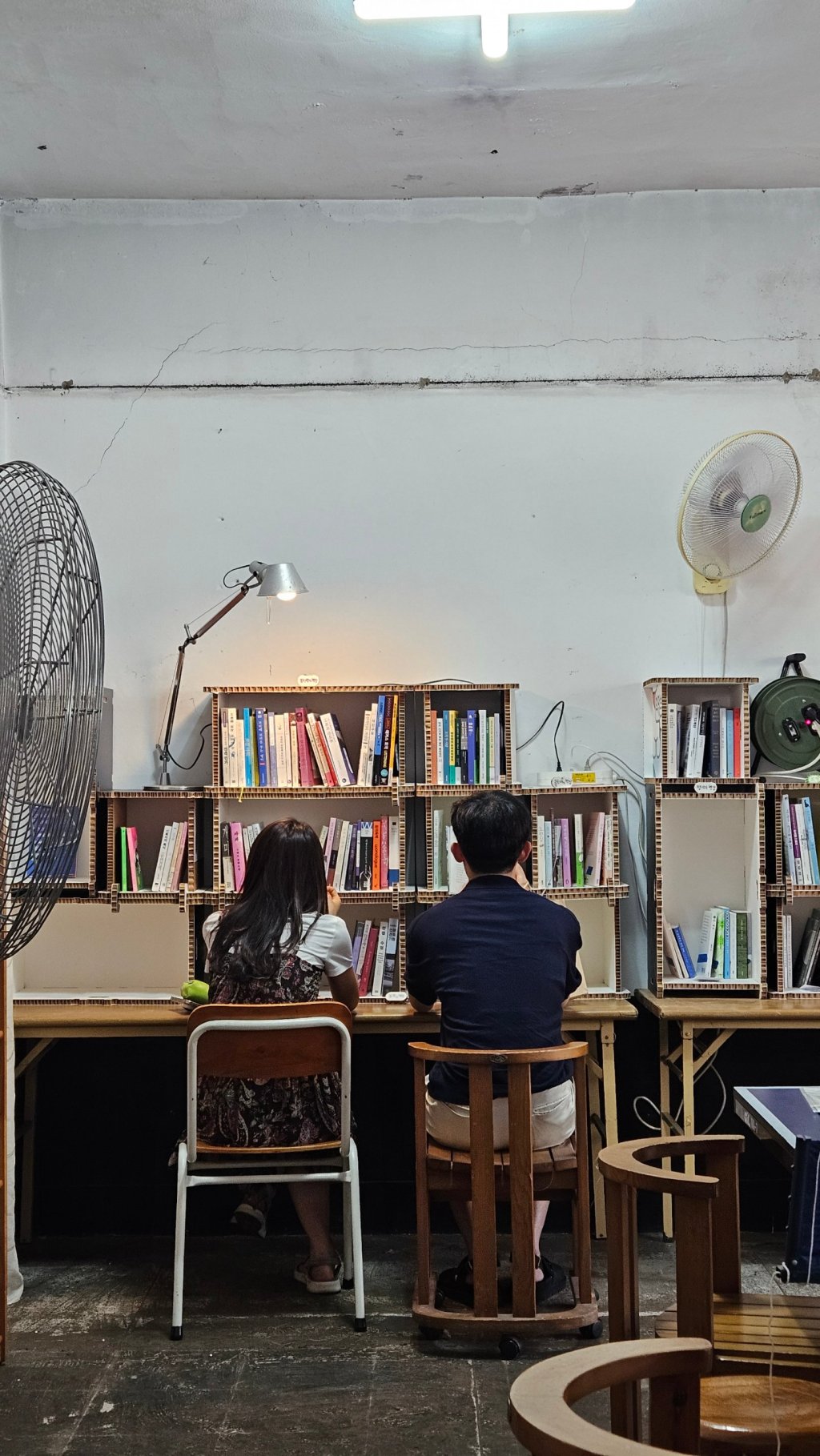 책장 앞에 나란히 앉아 책을 고르는 두 방문객